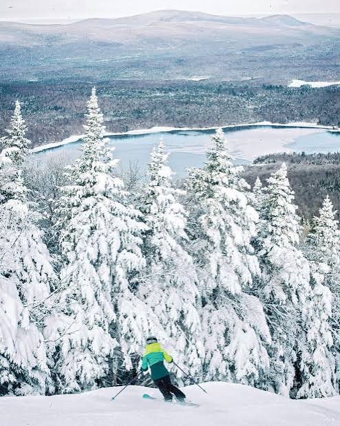 Skier descending Mount Snow with a lake view